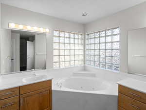 Bathroom featuring plenty of natural light, a tub, a textured ceiling, and vanity