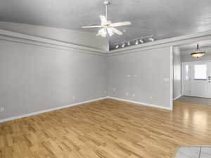 Unfurnished room with lofted ceiling, track lighting, light wood-type flooring, and ceiling fan