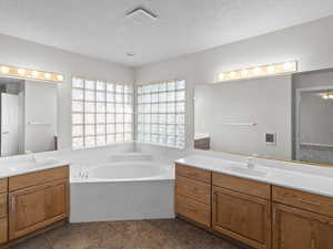 Bathroom with a bath, vanity, tile patterned flooring, and a textured ceiling