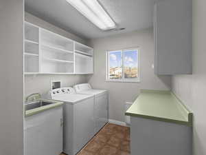 Laundry room featuring a textured ceiling, cabinets, washer and clothes dryer, and sink