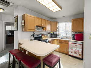 Kitchen with electric range, dishwasher, sink, kitchen peninsula, and a breakfast bar