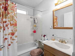 Full bathroom featuring vanity, toilet, and shower / bathtub combination with curtain