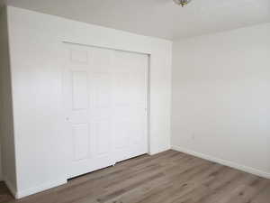 Unfurnished bedroom with a closet, hardwood / wood-style floors, and a textured ceiling