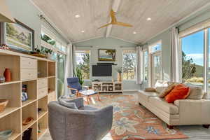 Living room with ceiling fan, light hardwood / wood-style floors, wood ceiling, and vaulted ceiling with beams