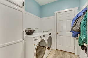 Laundry area featuring washer and dryer, light hardwood / wood-style flooring, and cabinets