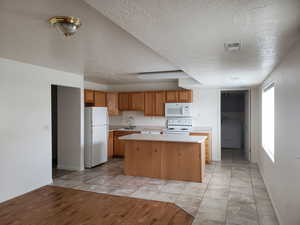 ADU Kitchen with white appliances, washer / dryer, a kitchen island, sink, and light tile patterned flooring