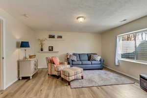 Family room/bedroom area featuring a textured ceiling and light hardwood / wood-style floors