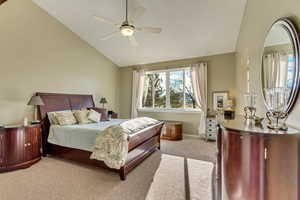 Carpeted bedroom featuring ceiling fan and high vaulted ceiling