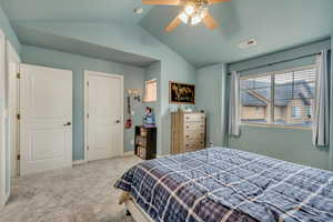 Bedroom featuring vaulted ceiling, ceiling fan, and light carpet