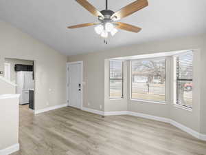 Living room featuring bay window, lofted ceiling, ceiling fan, and light  wood-style flooring