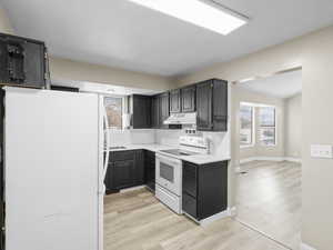 Kitchen featuring white appliances, light  wood-style floors and tasteful backsplash