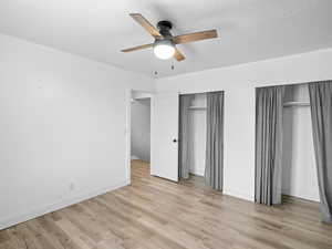 Unfurnished bedroom with multiple closets, ceiling fan, and light wood-type flooring