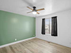 Spare room with a textured ceiling, ceiling fan, and light wood-style floors