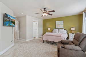 Large Primary Bedroom with ceiling fan and light colored carpet.