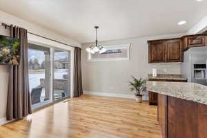 Kitchen featuring an inviting chandelier, stainless steel refrigerator with ice dispenser, hanging light fixtures, and dark brown cabinetry