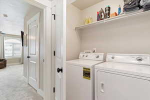 right outside Primary Bedroom Washroom with a textured ceiling, washing machine and dryer, and light carpet