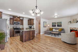 Kitchen featuring stainless steel appliances, dark brown cabinetry, a chandelier, and pendant lighting