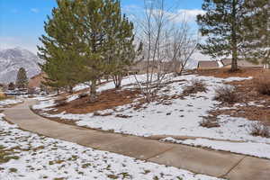 walk path in the community. Yard covered in snow featuring a mountain view