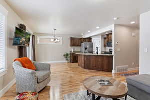 from the fireplace, looking into kitchen. Living room with sink, light hardwood / wood-style floors, and a chandelier