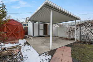 Snow covered patio featuring a shed