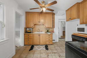 Kitchen featuring ceiling fan, sink, black dishwasher, light tile patterned flooring, and tasteful backsplash