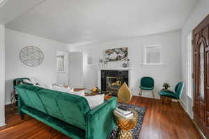 Living room featuring wood-type flooring, a tile fireplace, and a textured ceiling