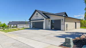 View of property exterior featuring a garage, driveway, stone siding, and stucco siding