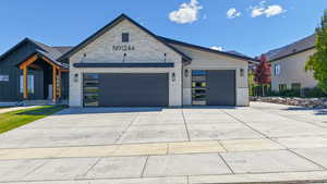 View of front of house with concrete driveway, a garage, and stone siding