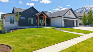 View of front of house with concrete driveway, a front lawn, a garage, and a mountain view