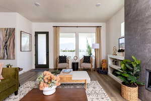 Living room with dark wood-type flooring, a textured ceiling, and a tiled gas fireplace. Photo of Finland Model Home not subject property