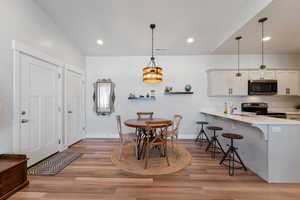 Dining room featuring light hardwood / wood-style floors, lofted ceiling, and sink