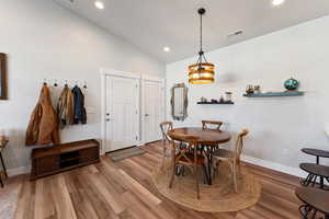 Dining room with a chandelier, wood-type flooring, and vaulted ceiling