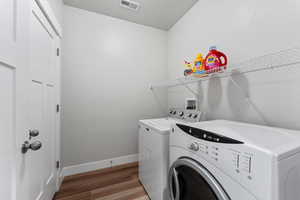 Laundry room with washing machine and clothes dryer and light hardwood / wood-style flooring