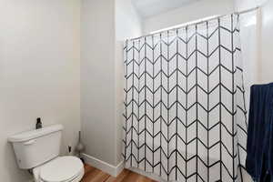 Bathroom featuring toilet, wood-type flooring, and walk in shower