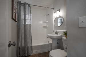 Bathroom featuring toilet, shower / tub combo, and hardwood / wood-style floors