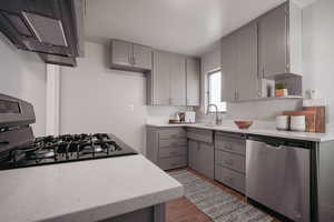 Kitchen featuring hardwood / wood-style flooring, stainless steel dishwasher, gray cabinets, and sink