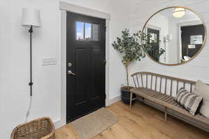 Entryway with light wood-type flooring and wood walls