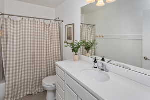 Full bathroom with toilet, tile patterned flooring, shower / tub combo, and vanity