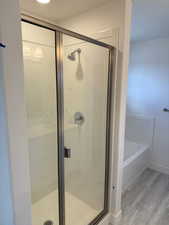 Bathroom featuring shower with separate bathtub and wood-type flooring