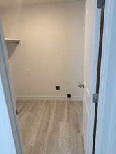 Clothes washing area featuring electric dryer hookup and light hardwood / wood-style flooring