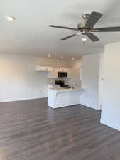 Kitchen featuring stainless steel appliances, white cabinetry, ceiling fan, and a breakfast bar