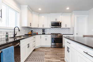 Kitchen featuring appliances with stainless steel finishes, dark stone counters, white cabinetry, and sink