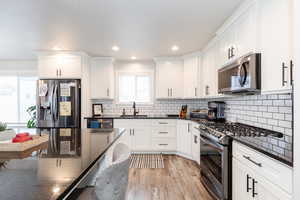 Kitchen with sink, white cabinetry, dark stone countertops, plenty of natural light, and appliances with stainless steel finishes