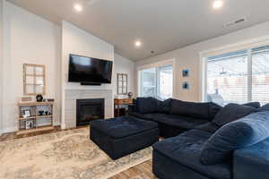 Living room with wood-type flooring, a fireplace, and vaulted ceiling