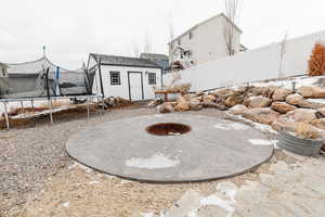 View of yard featuring an outdoor fire pit, a trampoline, and a storage shed