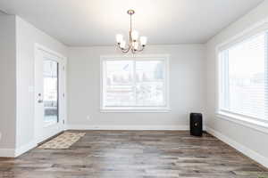 Unfurnished dining area with an inviting chandelier and hardwood / wood-style flooring