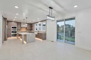 Kitchen with a center island, a breakfast bar area, decorative backsplash, pendant lighting, and appliances with stainless steel finishes