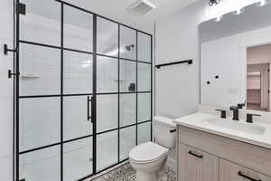 Bathroom featuring toilet, a shower with door, tile patterned floors, and vanity