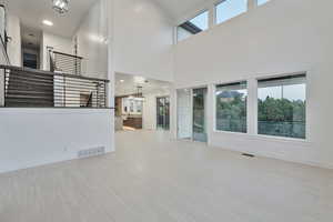 Unfurnished living room featuring a towering ceiling, sink, and light tile patterned floors