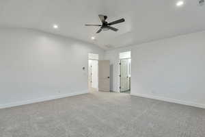 Unfurnished bedroom with ceiling fan, light colored carpet, and vaulted ceiling